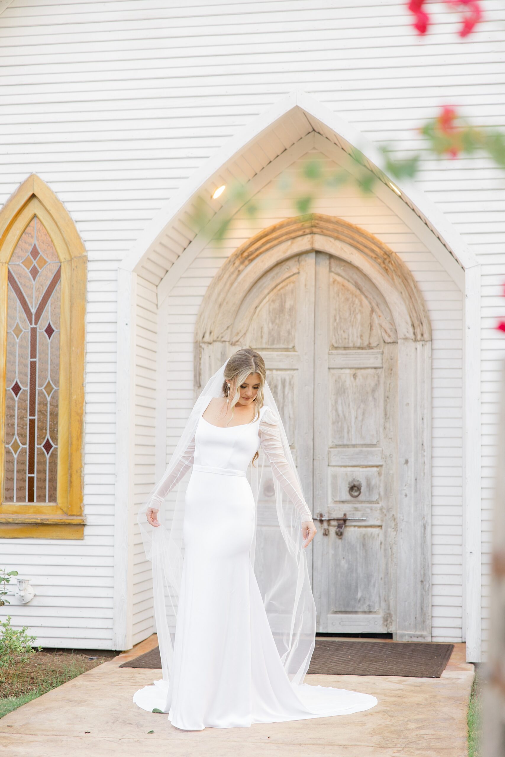 bride poses outside wooden door atThe Brooks at Weatherford