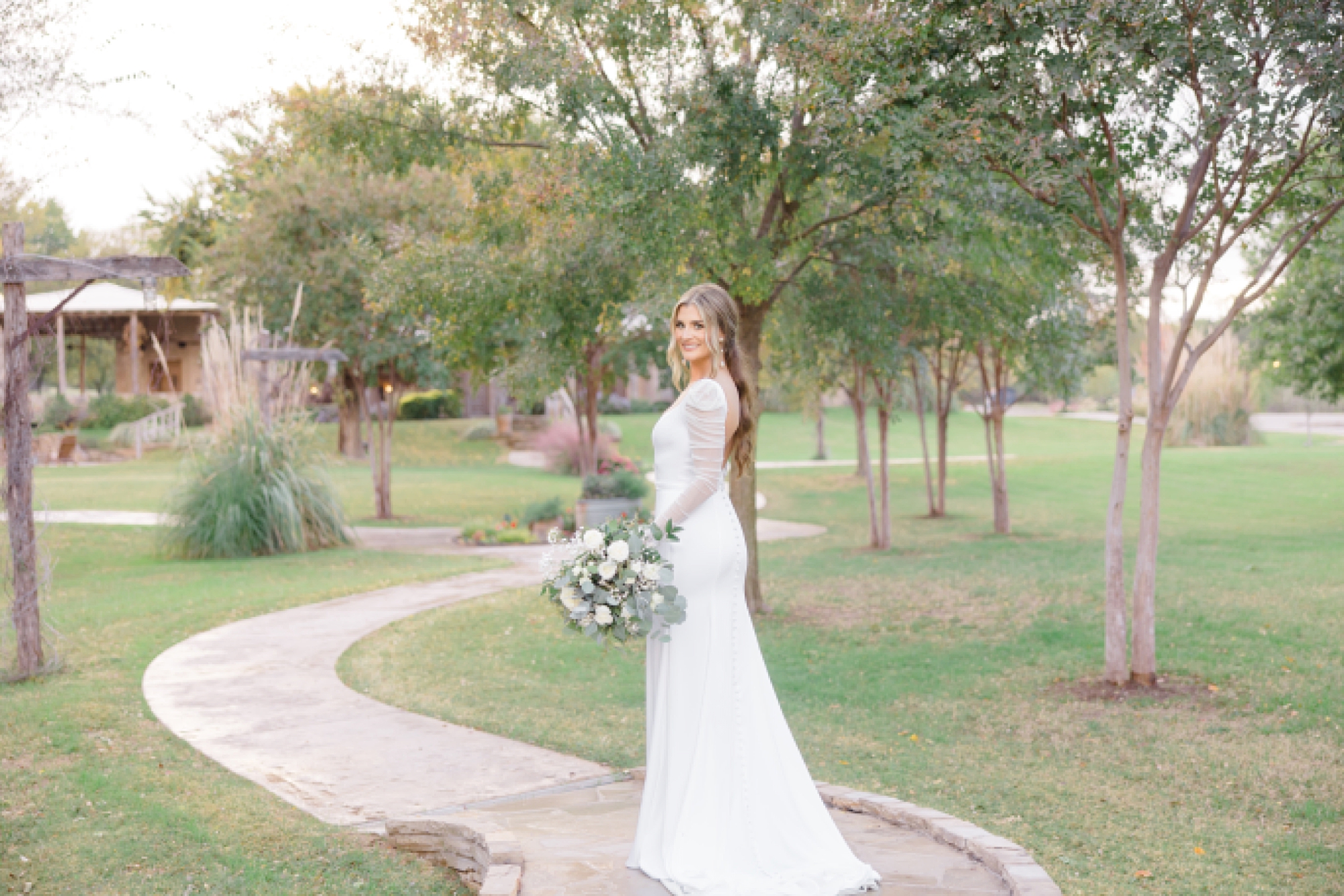bride stops on path looking over shoulder during The Brooks at Weatherford bridal session