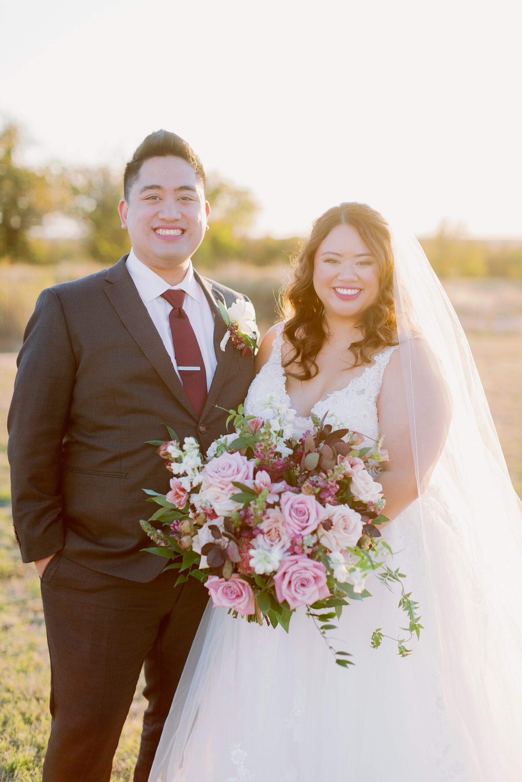 newlyweds smile with sunset glow behind them 