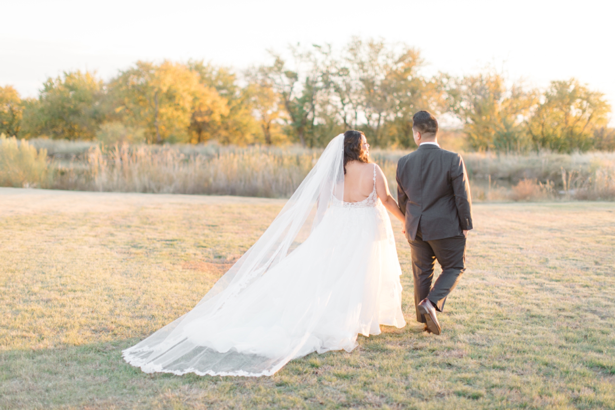 newlyweds walk on lawn by pond at The Nest at Ruth Farms