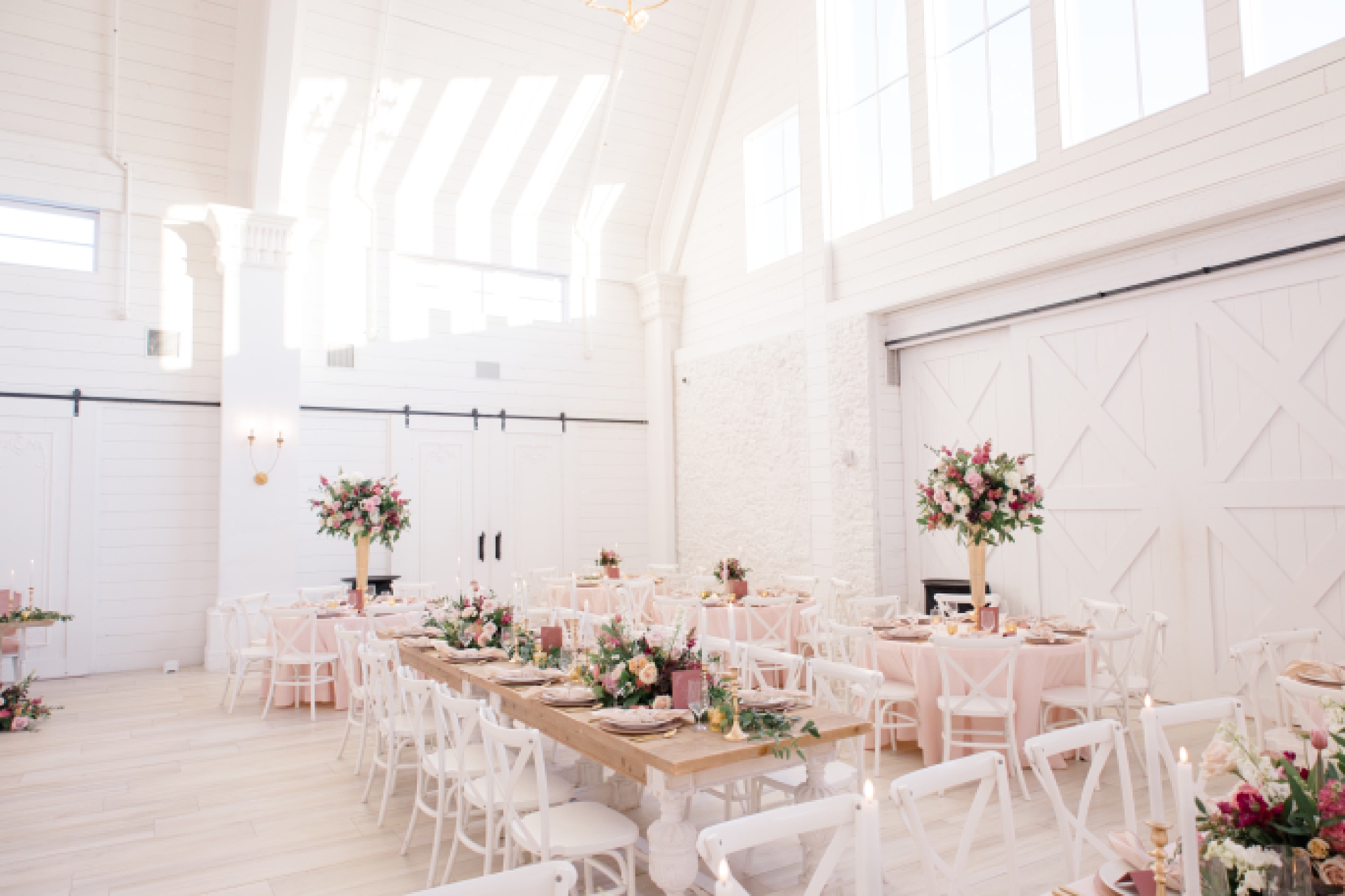 winter Nest at Ruth Farms wedding reception with white chairs, pink napkins and tall floral centerpieces 