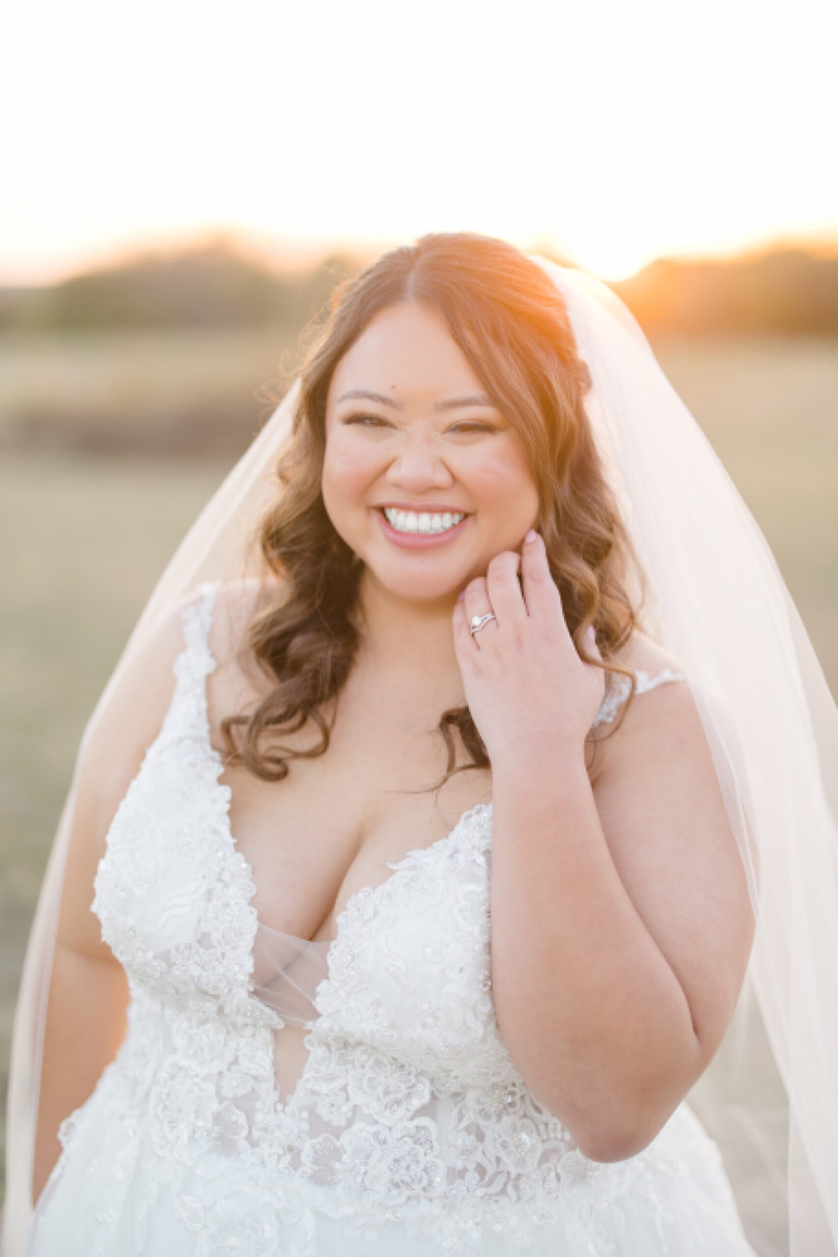 bride smiles pushing hair over shoulder during sunset portraits 