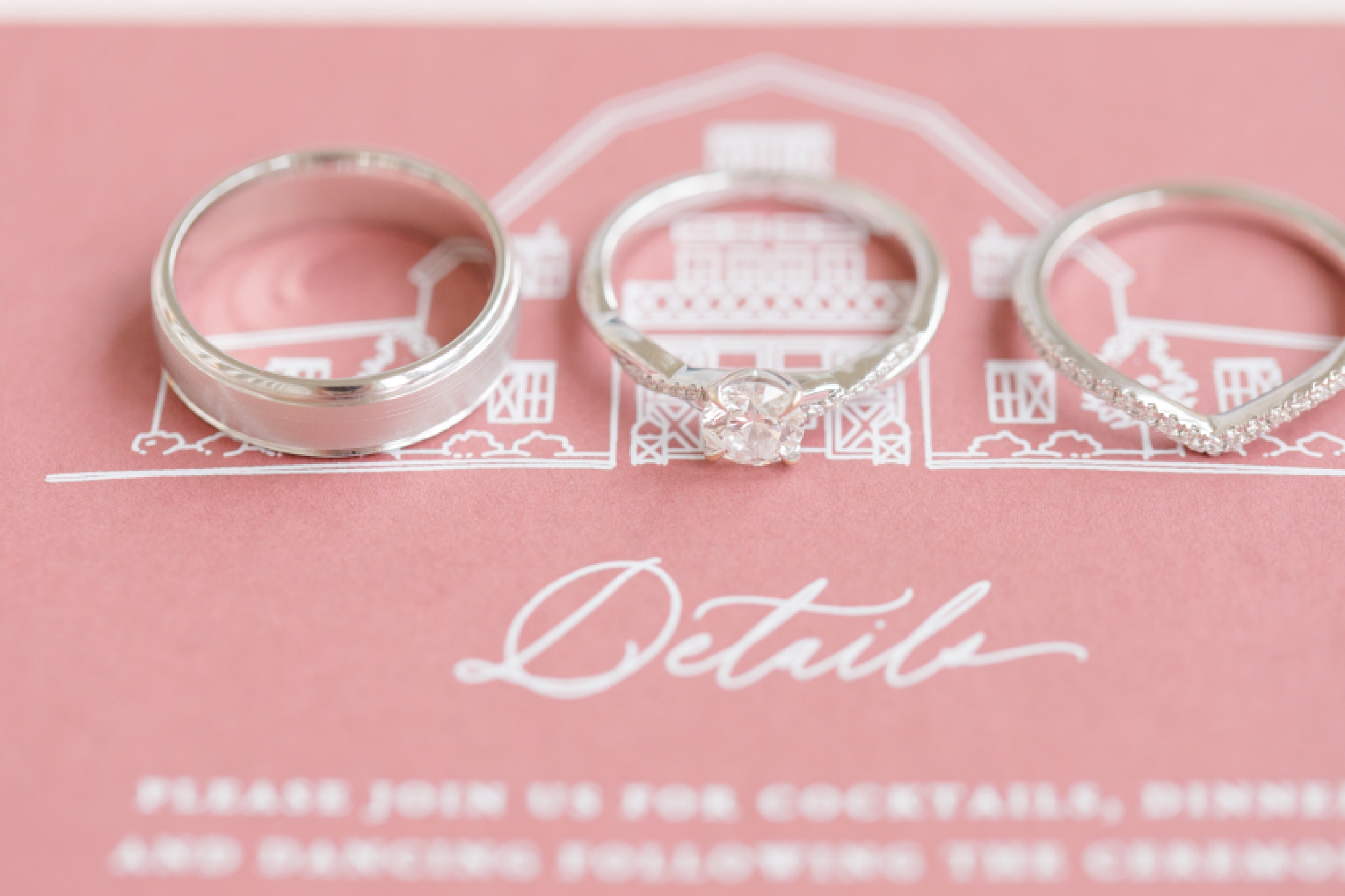 three wedding rings lay on pink and white invitation suite for winter wedding 