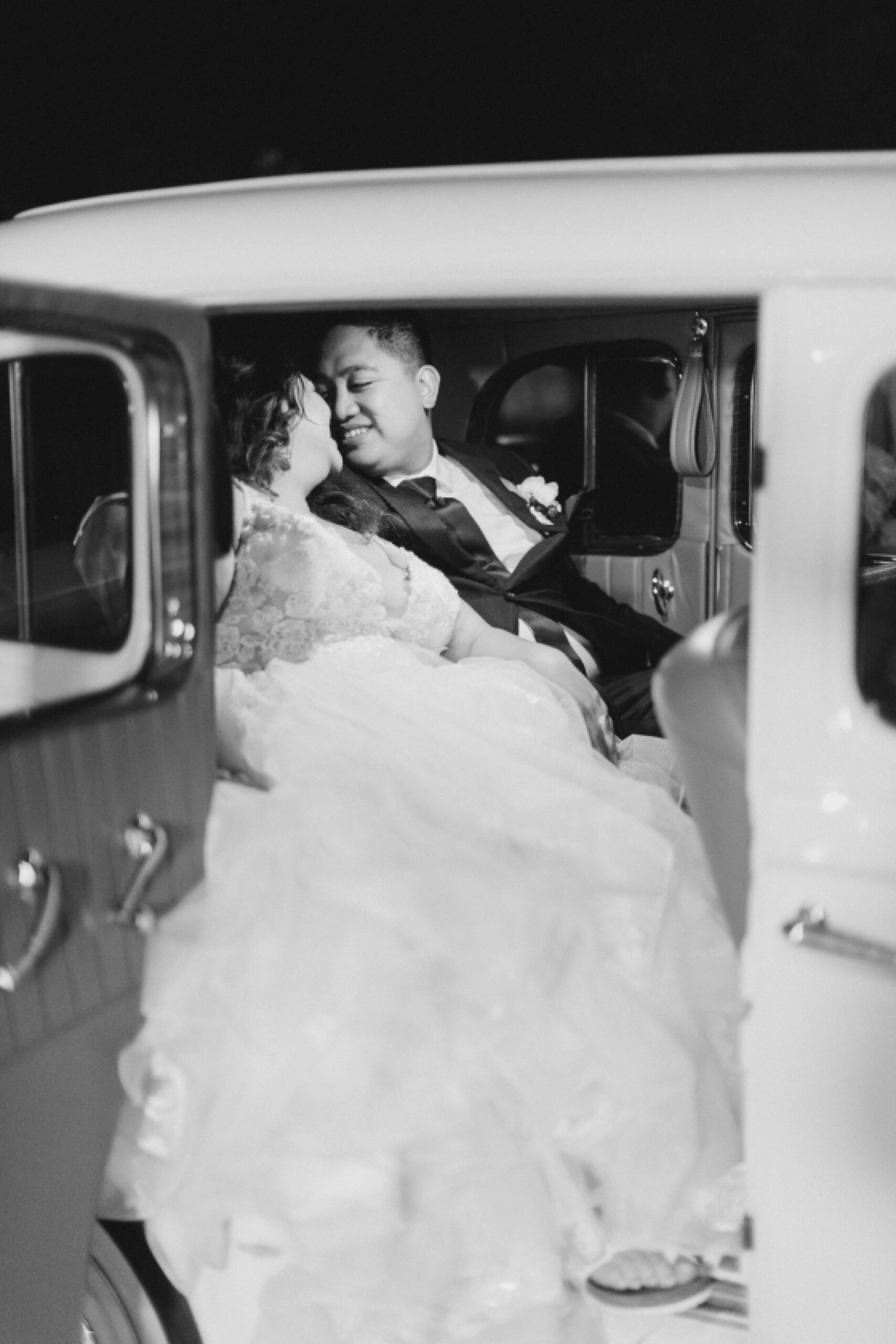 newlyweds cuddle together in back of vintage car 