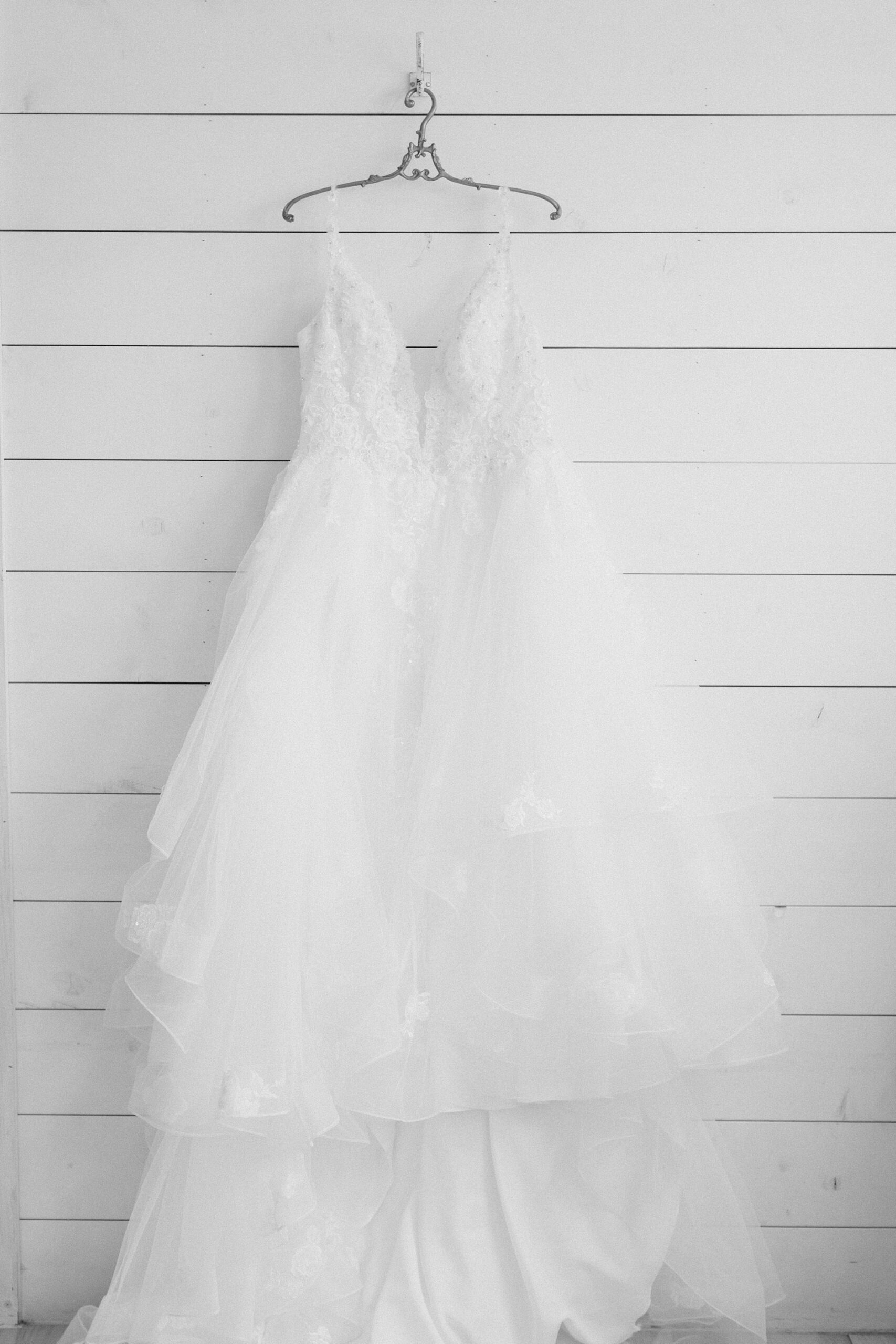 wedding dress hangs on custom hanger on white shiplap wall at The Nest at Ruth Farms 