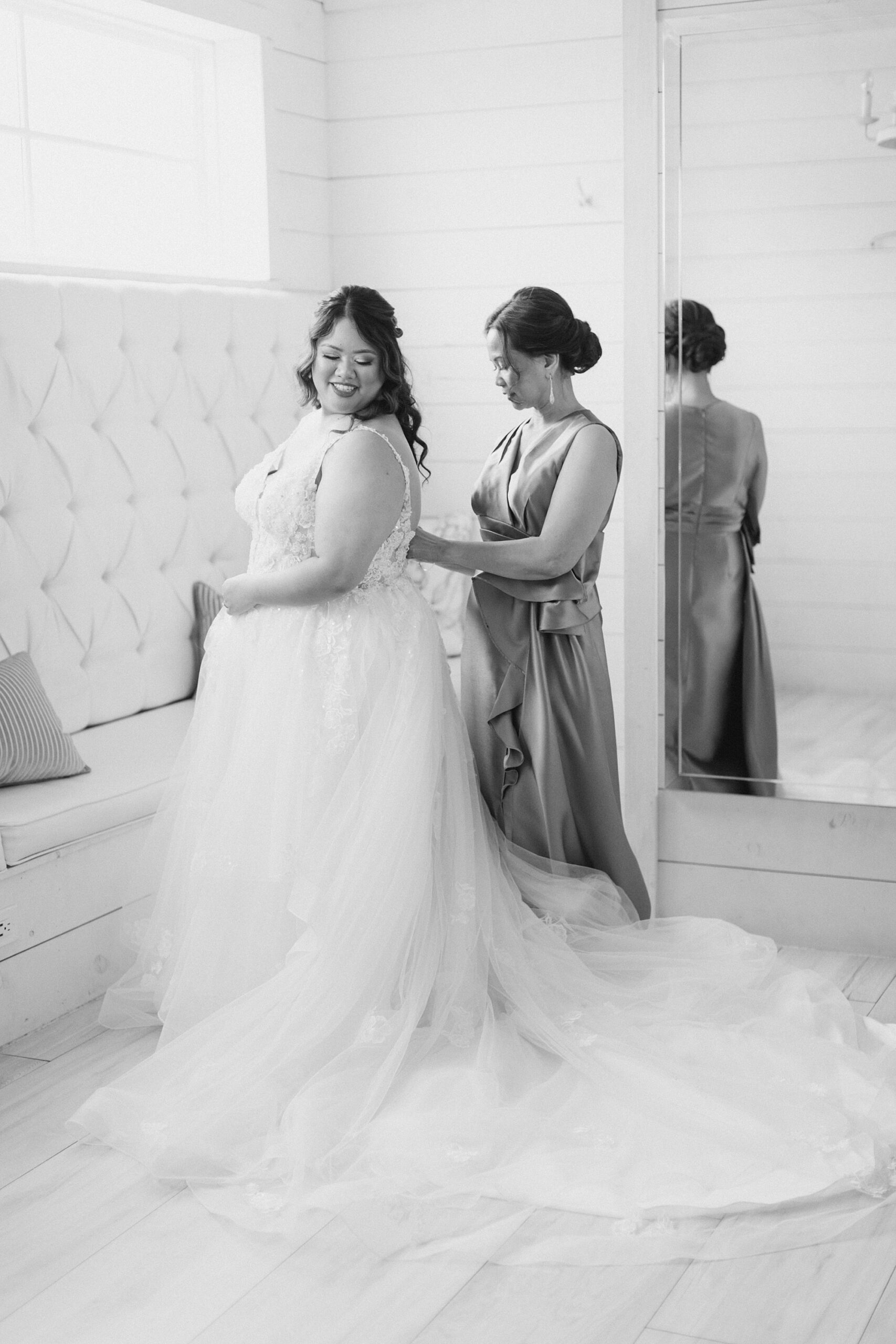 mother helps bride into wedding gown by mirror in suite at The Nest at Ruth Farms