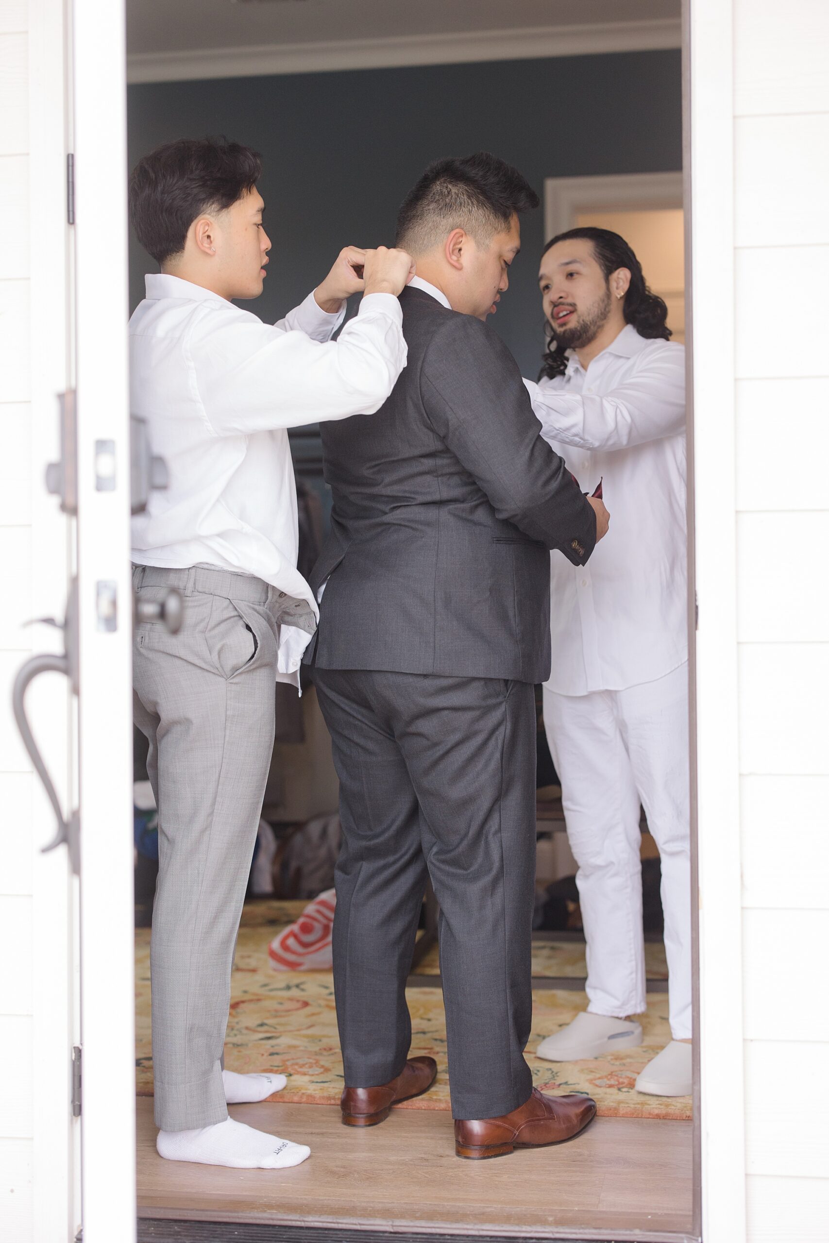 groomsmen help groom with tie