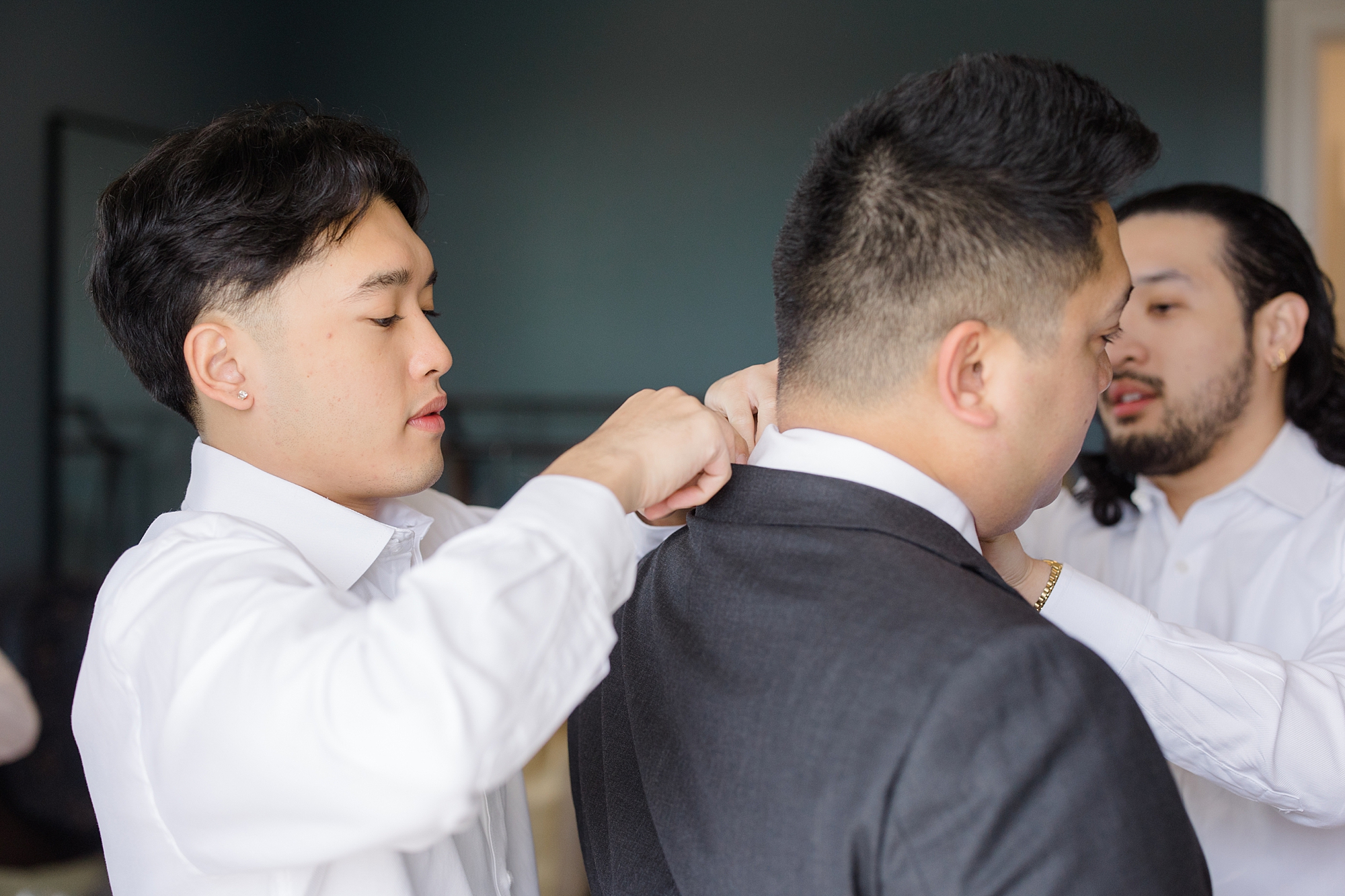groomsman helps groom with tie and collar 
