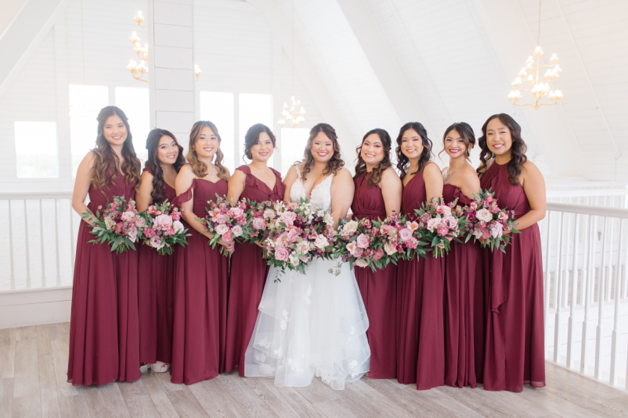 bride poses with bridesmaids in burgundy gowns on balcony at The Nest at Ruth Farms