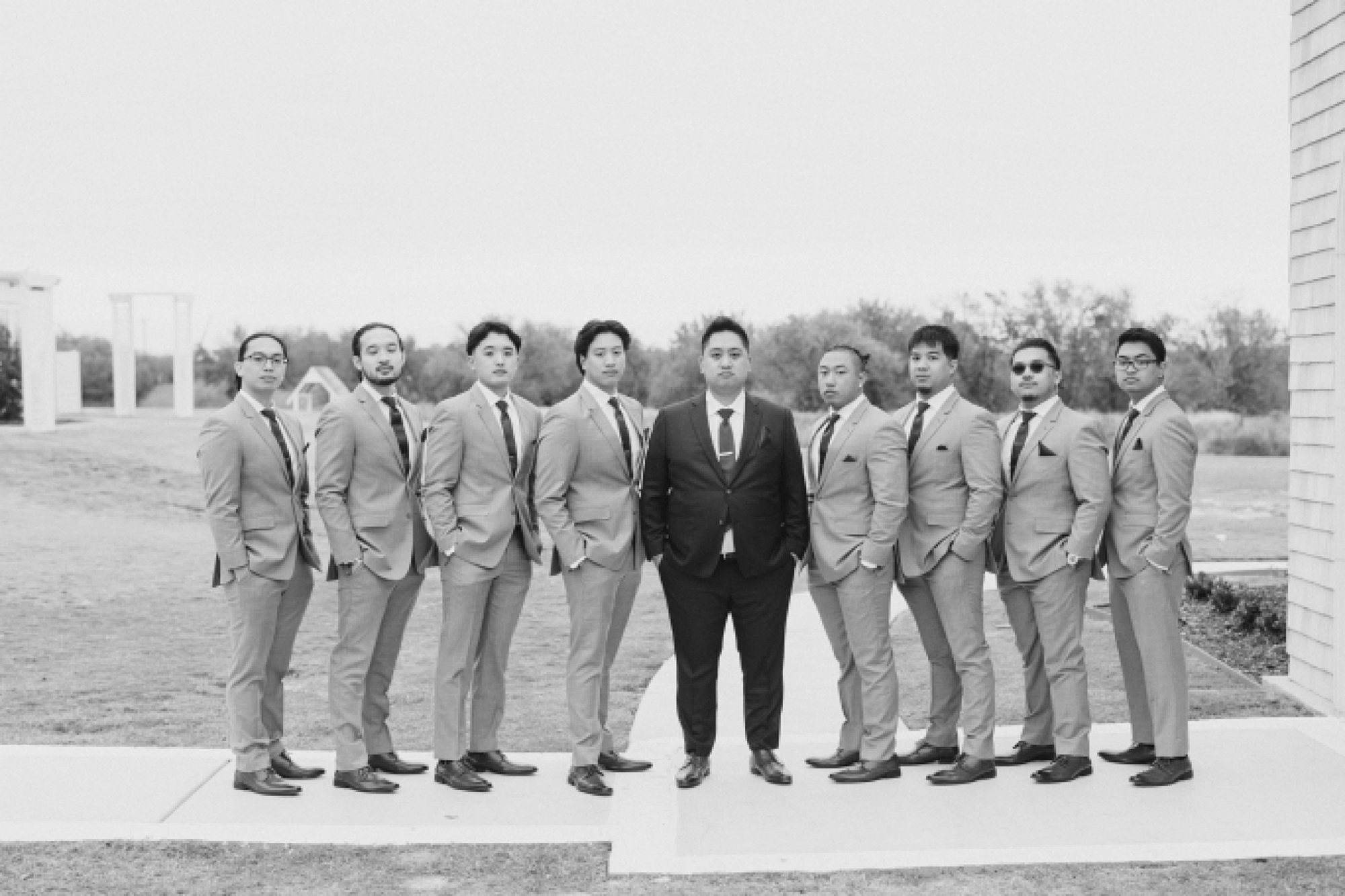 groom stands with groomsmen in grey suits outside church 